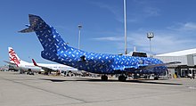 An Alliance Airlines Fokker 70 at Brisbane Airport, wrapped in Powerball wrapping paper (December 2016) Alliance Airlines Fokker F70 wrapped up at Brisbane Airport (cropped).jpg