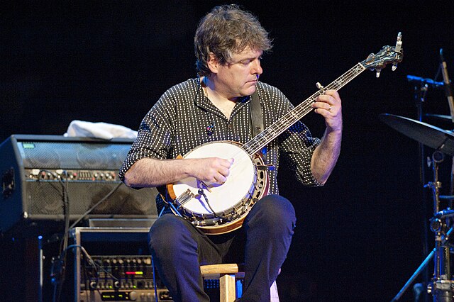 A man sat down playing banjo.