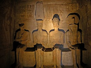 Statuen von vier sitzenden Figuren in einem schwach beleuchteten Raum