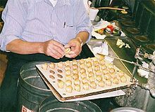 Hot fortune cookies being folded around paper fortunes at Golden Gate Fortune Cookie Factory Fortune cookie factory.jpg