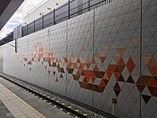 Concrete retaining wall with orange-red coloured triangles inscribed on it