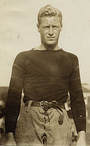 Young man shown from the waist up squinting towards the camera