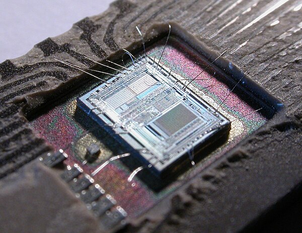 The die from an Intel 8742, an 8-bit microcontroller that includes a CPU running at 12 MHz, 128 bytes of RAM, 2048 bytes of EPROM, and I/O in the same