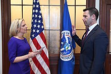 Kevin McAleenan being sworn in as DHS Acting Secretary by Kirstjen Nielsen in April 2019. DHS used this photograph to argue that Nielsen had intended to and had legally placed McAleenan next in line to become Acting Secretary, validating the later appointments of Wolf and Cuccinelli. Kevin McAleenan sworn-in as DHS Acting Secretary.jpg