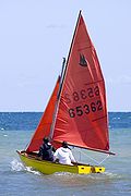 A Mirror dinghy, with two teenage girls on board, sails out from Brighton beach in South Australia.