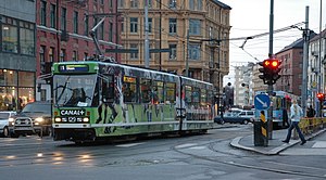 A tram with advertisements at a busy intersection