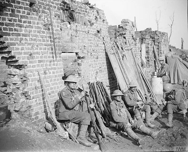 Troops of the Dorsetshire Regiment resting and cleaning rifles in the ruins of a farm near Langemarcke, 17 October 1917.