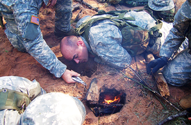 US Army aviation SERE students create a Dakota hole to conceal a fire in order to better protect their position from enemy observation. US Army SERE Training Photo.png