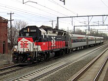A train with a diesel locomotive in a red, white, and black paint scheme