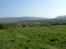 À travers le site envahi par la végétation du fort où il ne reste aucun mur avec les collines de Tintwistle et Peak Naze derrière