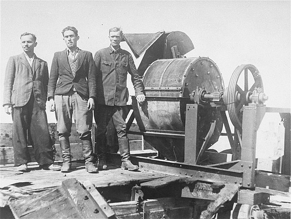 Survivors of the camp's Sonderkommando 1005 unit stand next to a bone crushing machine (taken following the liberation of the camp in 1944)