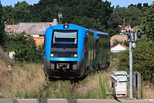 Két X 73500 típusú vasúti kocsi érkezik az állomásra. Ez a fotó azt mutatja, hogy a pálya benőtt fűvel.