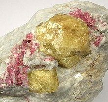 a lump of rock, with some yellow crystals and red crystals embedded into it