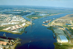 Aerial view of the Mobile River at its confluence with Chickasaw Creek, about 5 miles (8 km) above Mobile Bay. This photograph was taken about 1990 during construction of the Cochrane-Africatown bridge carrying U.S. Route 90 across the river. The bridge piers and construction crane are visible in the picture.