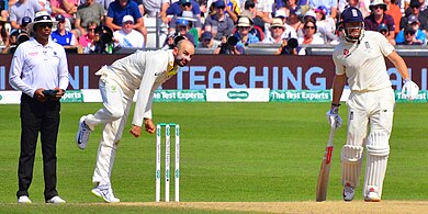 Lyon bowling while the non-striker and umpire watch