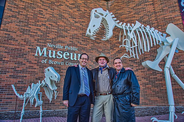 The County Executive Troy Streckenbach, Brown County Neville Museum Director, and Mayor Jim Schmitt of Green Bay in front of the dinosaur sculpture.