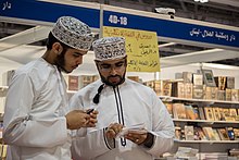 عکس از دو جوان مسلمان عرب، با پوشش مردم عمان در نمایشگاه بین‌المللی کتاب مسقط