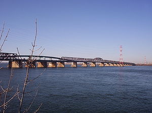 The numerous truss sections of a long bridge across a large body of water.