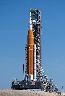 A launch vehicle beside a tower on pad