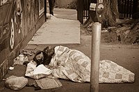 A homeless man sleeping in a parking lot.