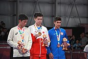 Deutsch: Tischtennis bei den Olympischen Jugend-Sommerspielen 2018: Tag 4, 10. Oktober 2018, Jungen-Einzel, Siegerehrung - Gold: Wang Chuqin (CHN), Silber: Tomokazu Harimoto (JPN), Bronze: Kanak Jha (USA); Medaillen überreicht durch IOC-Mitglied William Frederick Blick (UGA), Maskottchen überreicht durch ITTF-Präsident Thomas Weickert (GER) English: Fencing at the 2018 Summer Youth Olympics at 10 October 2018 –Boys' single medail ceremony – Gold: Wang Chuqin (CHN), Silber: Tomokazu Harimoto (JPN), Bronze: Kanak Jha (USA)); Medal presenter: IOC member William Frederick Blick (UGA), Mascot presenter: ITTF President Thomas Weickert (GER)