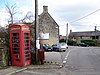 Escena callejera.  Cabina de teléfono roja y poste de telégrafo.  Edificios de piedra alrededor del cruce de carreteras.