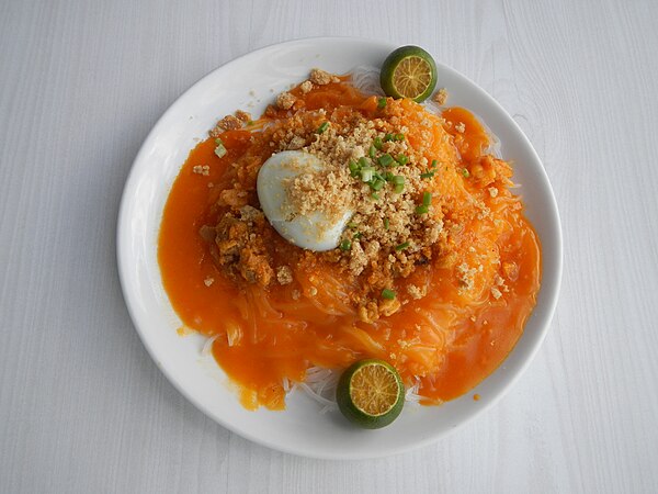 Pancit palabok in Filipino cuisine, combines rice noodles and tofu from China with native smoked fish flakes in a shrimp sauce dyed bright orange with