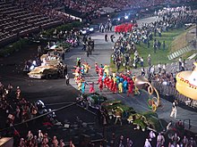 photo couleur d'une parade dans un stade olympique, prise depuis le haut des gradins