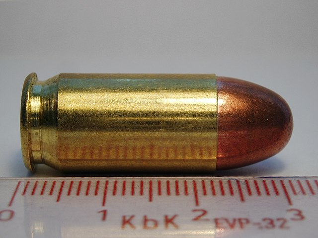 Side view of a Sellier & Bellot 45-cal ACP cartridge with a metric ruler for scale