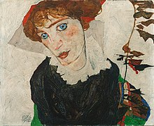 Portrait en plan poitrine d'une femme rousse aux yeux bleus vêtue de noir, tête penchée vers sa droite, tige de fleurs à sa gauche