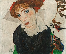 Portrait en plan poitrine d'une femme rousse aux yeux bleus vêtue de noir, tête penchée vers sa droite, tige de fleurs à sa gauche