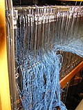 A loom from the back, in the process of warping, showing a shaft of threaded heddles. Heddle2.JPG