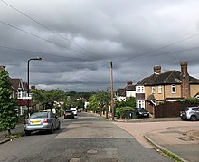 View down Henry's Avenue showing the architecture typical of the Highams Estate, and its proximity to the City of London, visible on the horizon. Henrys Avenue, Highams Estate.jpg