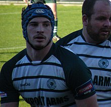 Homme avec un maillot vert et blanc coiffé d'un casque de rugby bleu