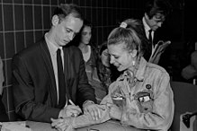 John Waters signing a fan's jean jacket sleeve at the Massachusetts College of Art in Boston, 1990. John Waters fan signature.jpg