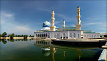 Photographie d'une mosquée bleu et blanc et de son bassin qui l'entoure.