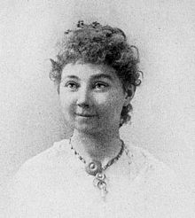 Portrait photograph of a middle-aged woman with her hair in an up-do, and wearing a high-collared blouse.