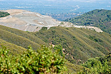 Waste quarry material piled over natural "Permanente Ridge" is visible from much of the South Bay. Natural "Permanente Ridge" buried by waste material by Lehigh Southwest Quarry 2012-07.jpg