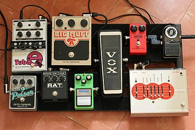 A guitar pedal board comprising several effects pedals, including vintage Electro-Harmonix Big Muff and Vox wah-wah pedals from the 1960s and 70s. Pedalboard (995939579).jpg