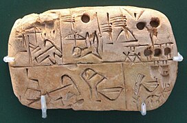 Tablette d'argile partagée en cases avec des logogrammes et signes numériques pictographiques.