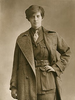 Portrait d'une femme aux cheveux courts avec un costume masculin et avec une main sur la taille.