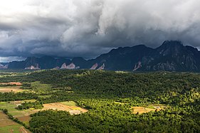 Lumière du soleil et ciel orageux au-dessus des montagnes et des rizières, vue sud-ouest depuis le sommet du mont Nam Xay, durant la mousson, à Vang Vieng.