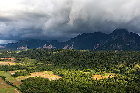 Sunlight and stormy sky over the mountains and paddy fields in Vang Vieng, Laos