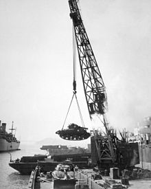 A crane hoisting a tank into a boat