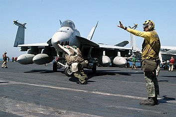 Pelaut mendorong sebuah F/A-18E Super Hornet dari VFA-115 untuk membantu penangan dalam mengarahkan sekitar dek penerbangan kapal USS Abraham Lincoln (CVN 72) pada tanggal 2 April 2003 selama OIF.