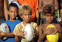 Solomon Islander boys from Honiara. People with brown or blond hair are quite common among Solomon Islanders without any European admixture, especially among children. A close up shot of three junior AFL player holding footballs at the Lord Howe Settlement, Honiara. (10661462334).jpg