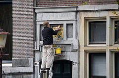 A man repainting a Coat of Arms. Amsterdam, The Netherlands