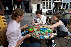 Young group playing RISK in a street cafe. Amsterdam, The Netherlands