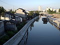 The buildings to the left, as well as the somewhat run-down boat, present a stark contrast to the modern high-rise buildings behind.The land to the right of the canal had been levelled ready for development, suggesting these buildings would not remain for that much longer.