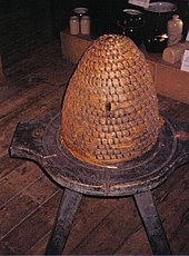 A bee skep at Dalgarven Mill. The base is part of an old cheese press. DalgarvenBeeSkep.jpg